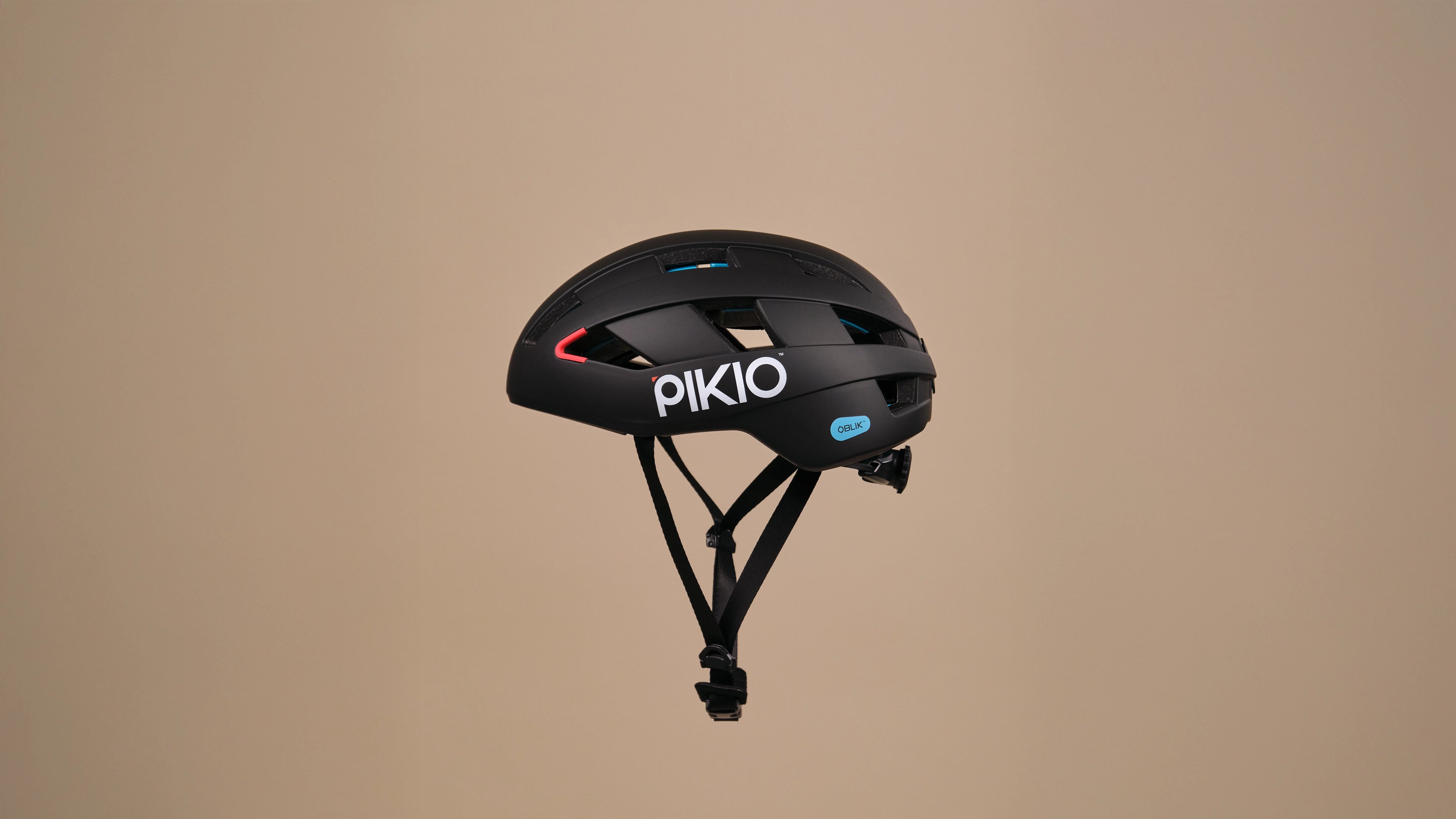 Black PIKIO Model Si helmet floating in front of a beige background