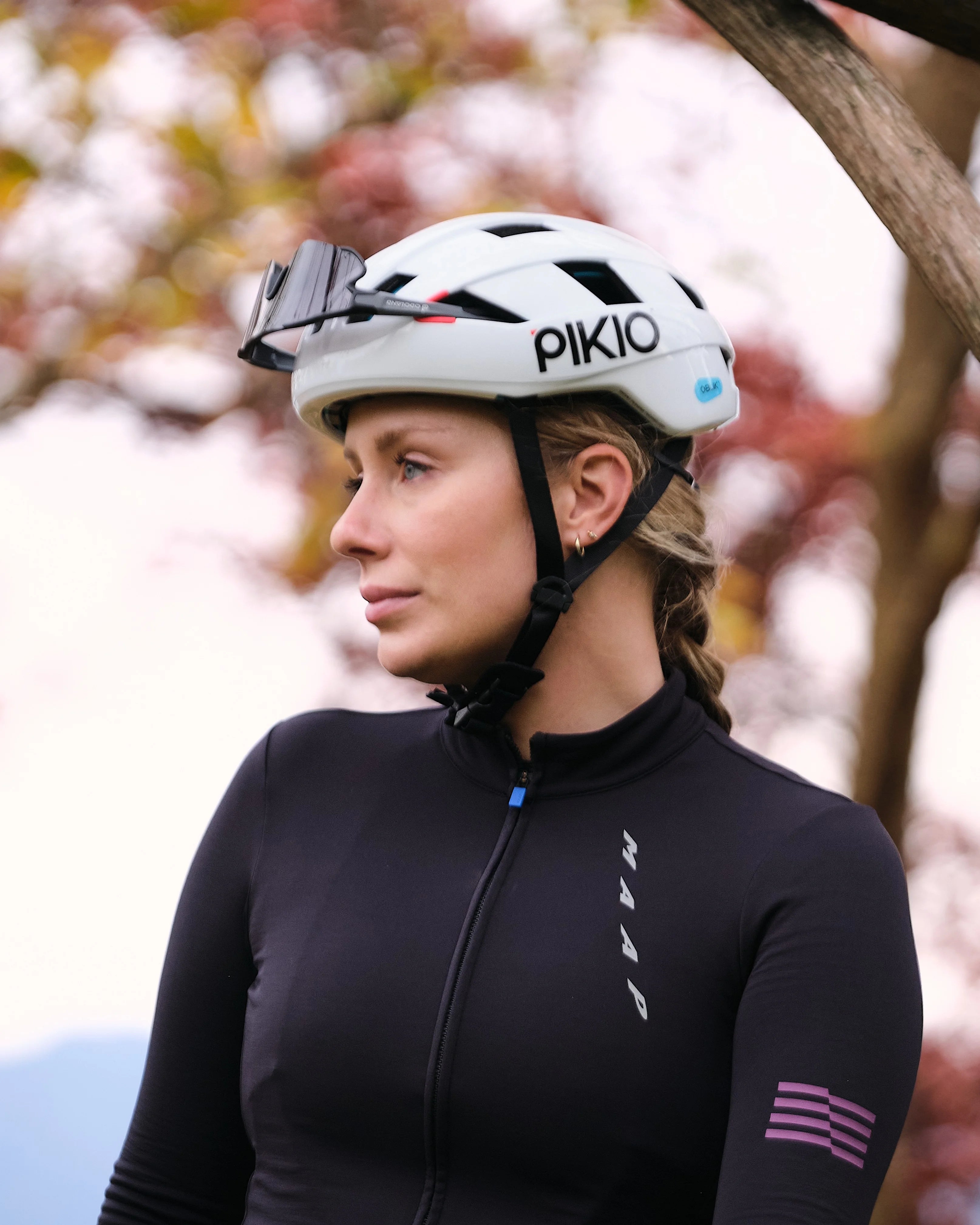 Person wearing a black cycling outfit and White PIKIO Si helmet outdoors.