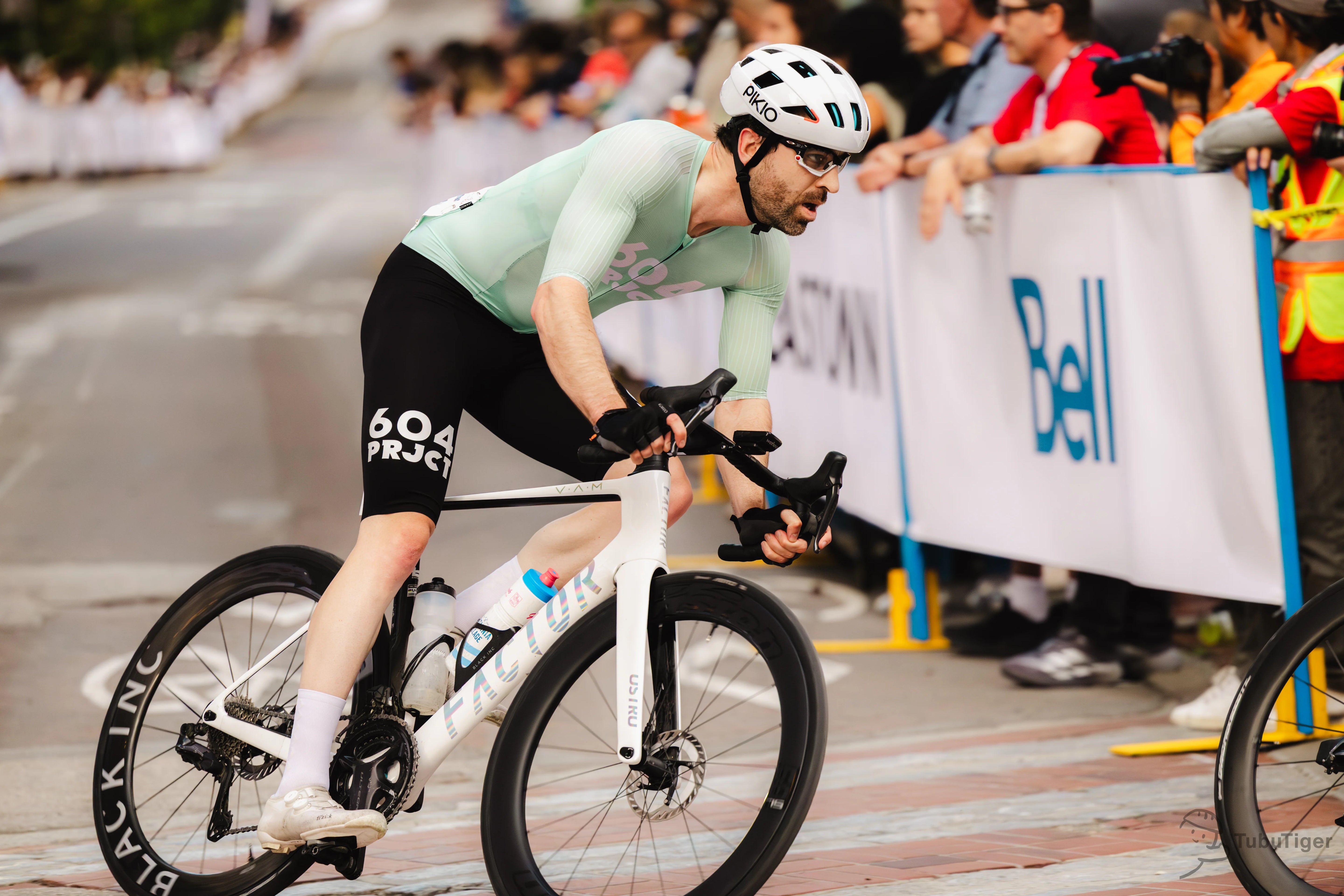 A cyclist racing with a white PIKIO Si OBLIK helmet